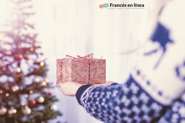 Una persona entraga un regalo de Navidad. En el fondo se ve el árbol de Navidad